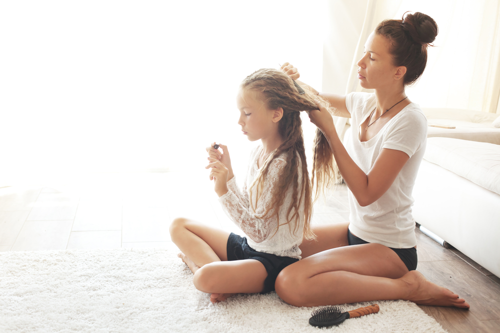 Young healthy mother combing daughter's hair