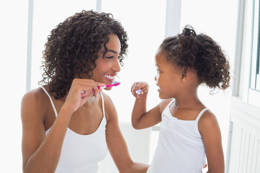 Young mother and daughter brushing their teeth