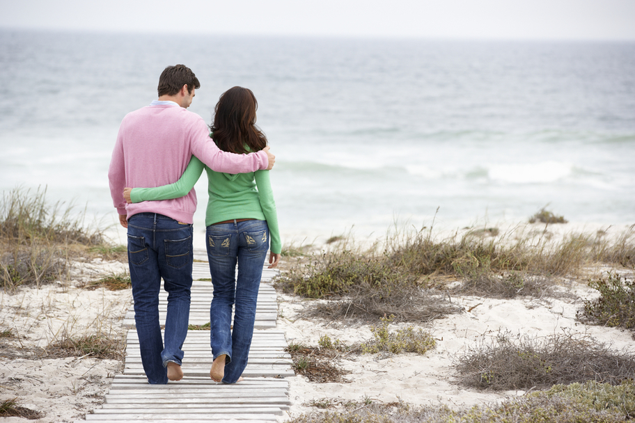 Man/woman couple walking on boardwalk at the beach