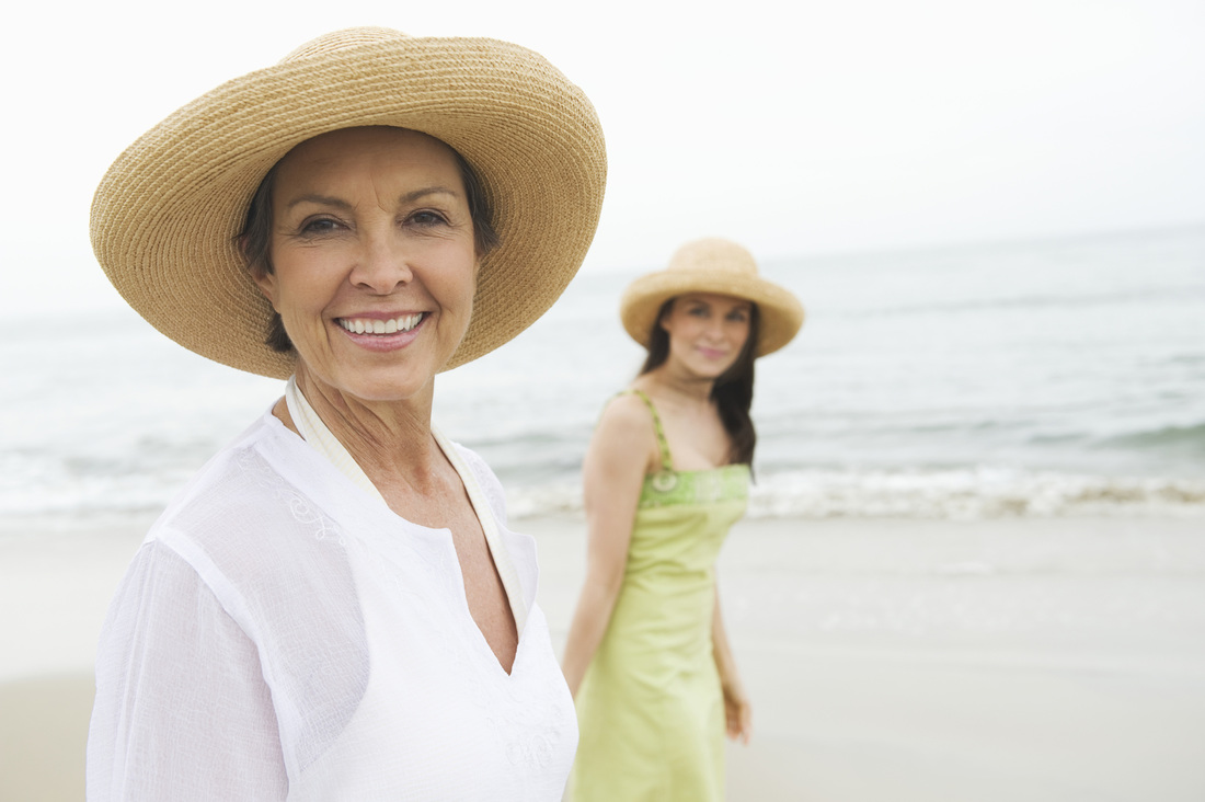 Smiling, confident, mature woman walking on beach with daughter