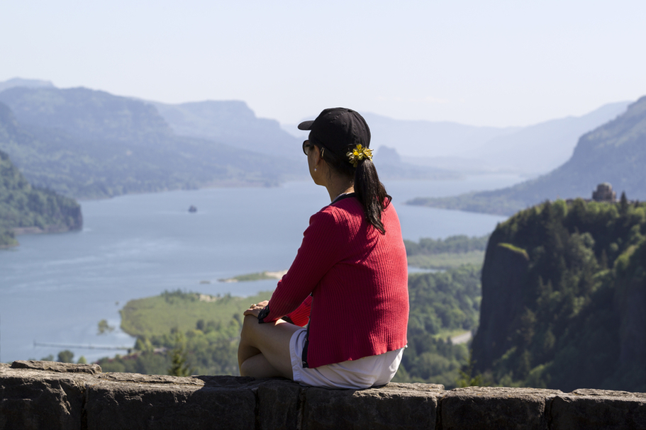 Woman sitting on stone wall overlooking a mountain lake